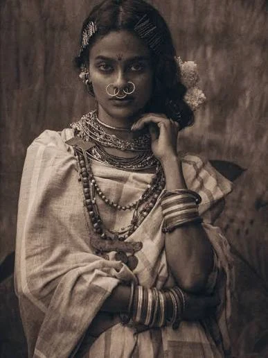 Portrait of a tribal woman wearing stacked neck rings, layered bead necklaces, twin nose rings and a row of hairpins