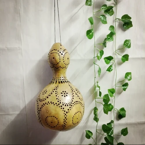 A dried bottle gourd worked into a hanging lamp, its surface pierced with concentric rings and floral dot patterns